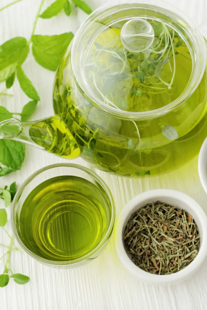 Pot of green tea with cup of tea and cup of green tea leaves