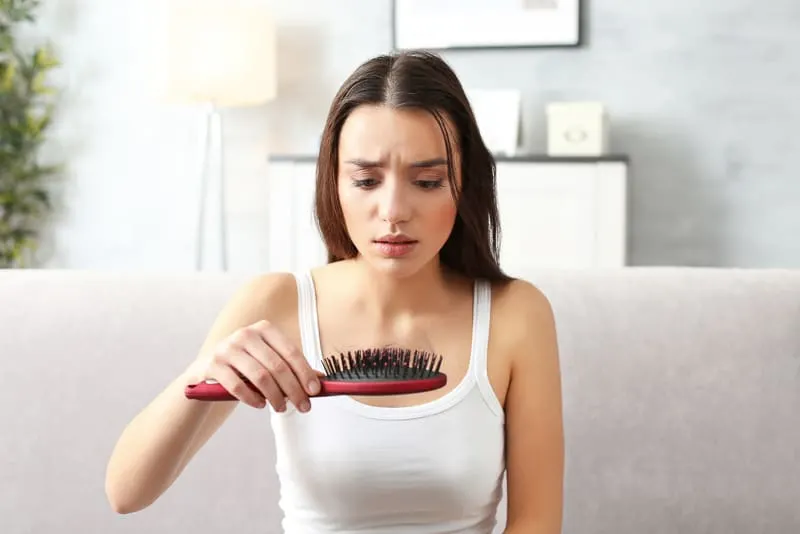 woman with hairbrush full of hair from hair loss