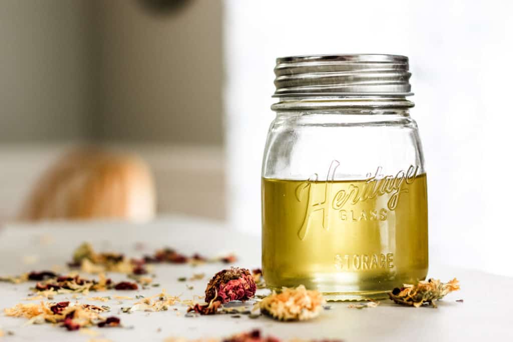 How to Quickly Make Herbal Infused Carrier Oils: Rose, Lavender and Calendula herbs being infused in a jar of carrier oil.