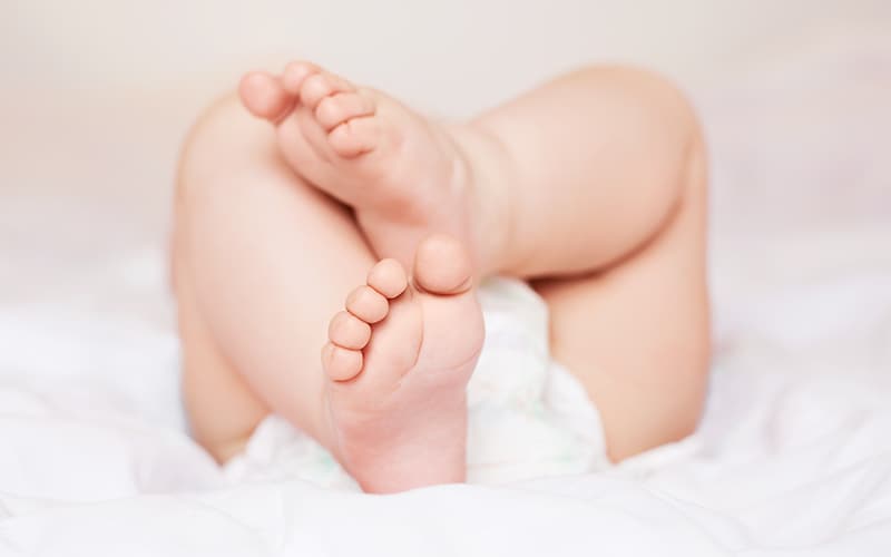 Baby lying down with feet and legs showing.