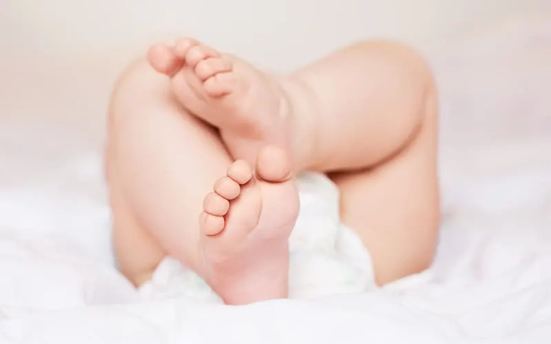 Baby lying down with feet and legs showing.