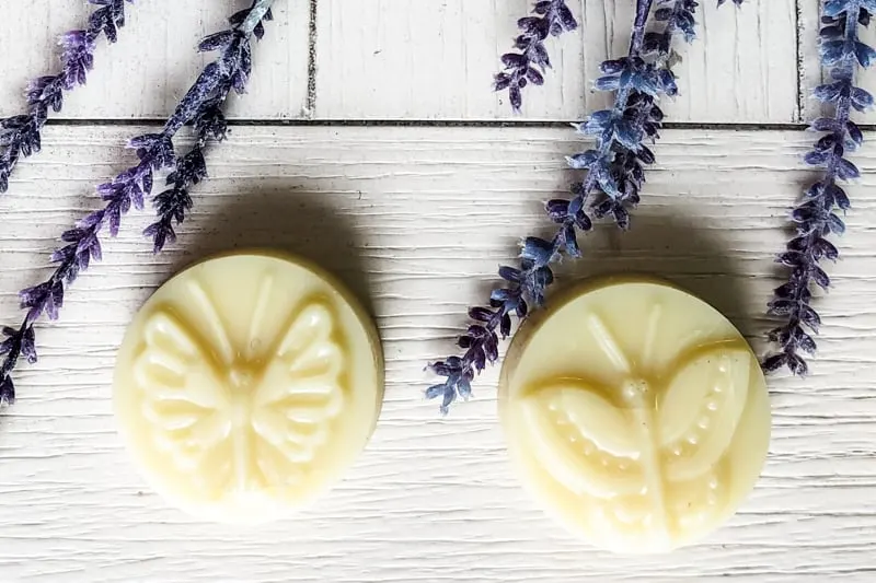 2 butterfly homemade cocoa butter lotion bars on a table with lavender