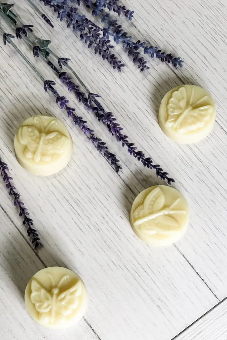 4 butterfly lotion bars on white table with lavender plants