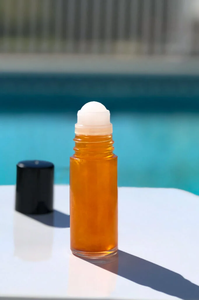 Roll-on bottle of diy shimmer body oil by pool