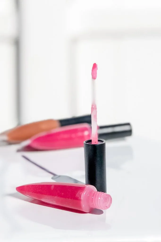 Open tube of bright pink diy lip gloss with 2 tubes in the background